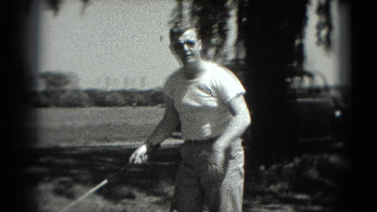 1975 Washington DC 8mm frame of a man holding a golf club near shaded tree cover, with open grass and a parked car visible behind him.