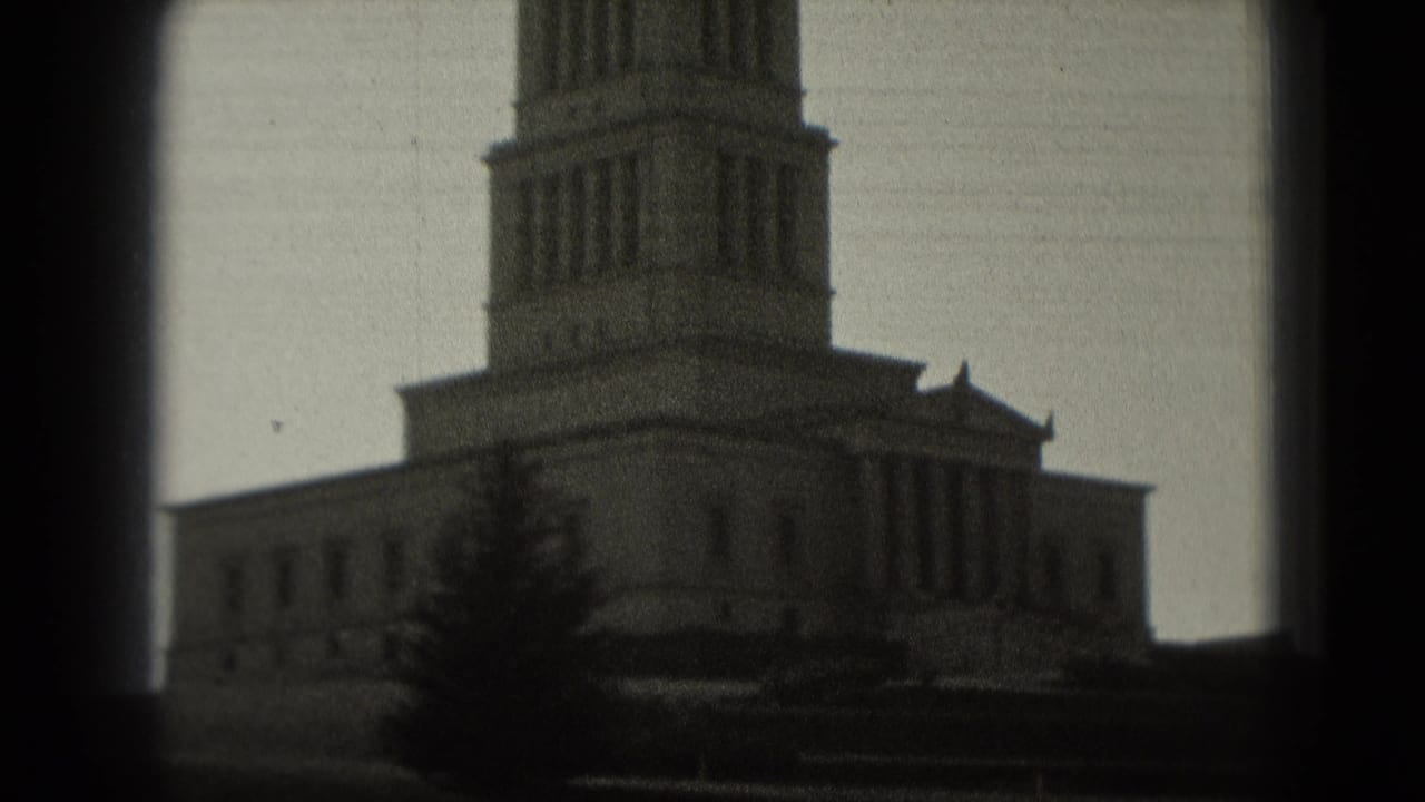 Soft 8mm view of a tall stone building tower partly framed by dark film edges.