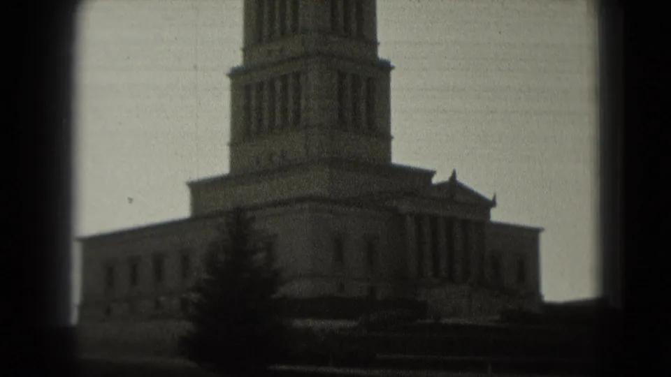 1975 Washington, DC home-movie frame showing a tall columned tower and stone building base in soft 8mm focus.