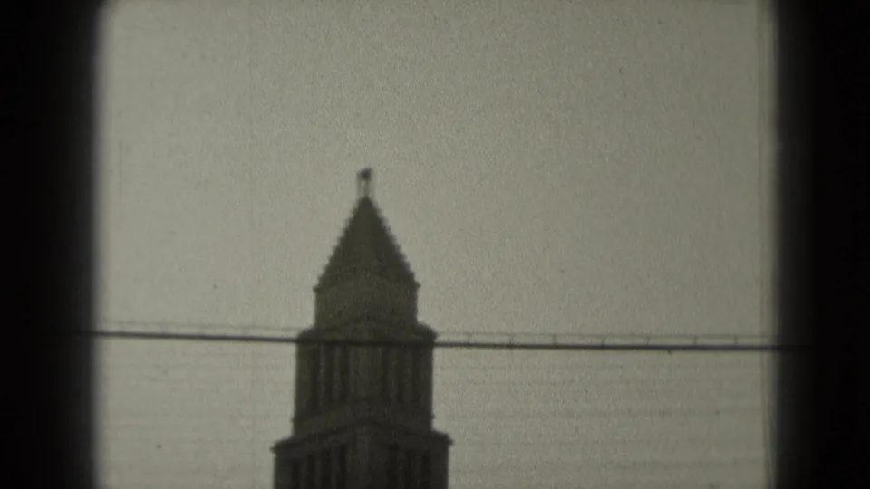 1975 Washington, DC frame showing the upper tower section with a small flag and overhead wire in soft 8mm texture.