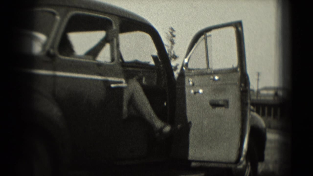 1975 Washington, DC 8mm frame showing a dark sedan with its passenger door open near a roadside railing.