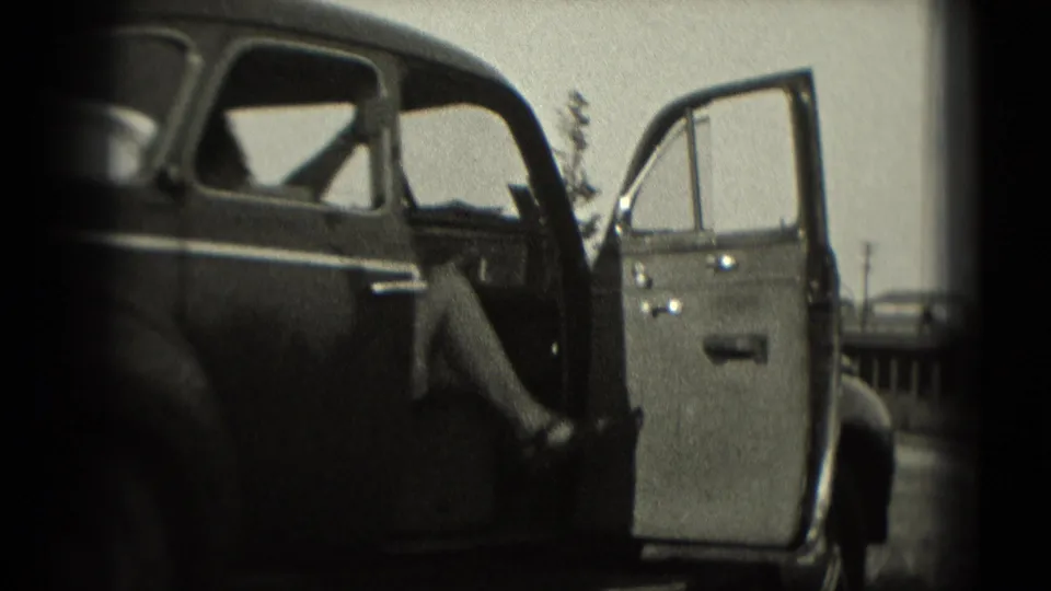1975 Washington, DC 8mm frame showing a dark sedan with its passenger door open near a roadside railing.
