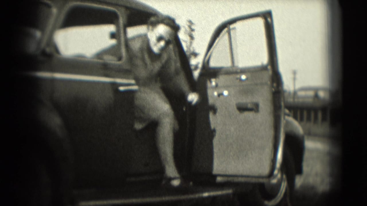 A woman begins stepping from a dark sedan in this 1975 Washington, DC home-movie frame.