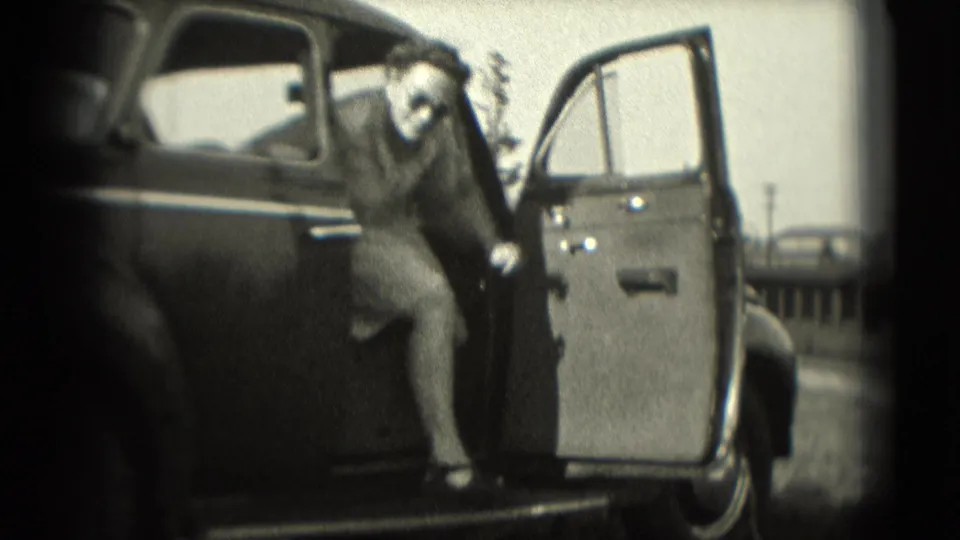 A woman begins stepping from a dark sedan in this 1975 Washington, DC home-movie frame.