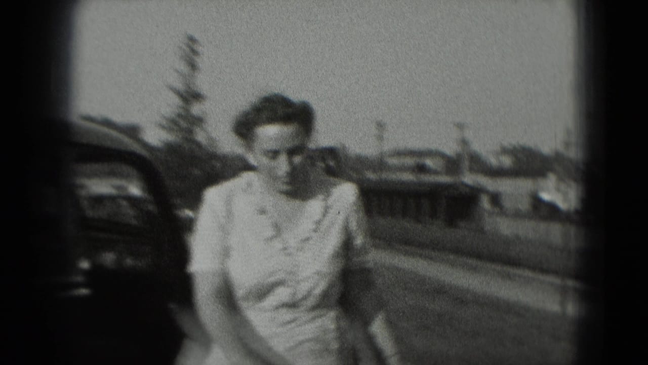 Woman in a light dress walking outdoors beside a parked car.