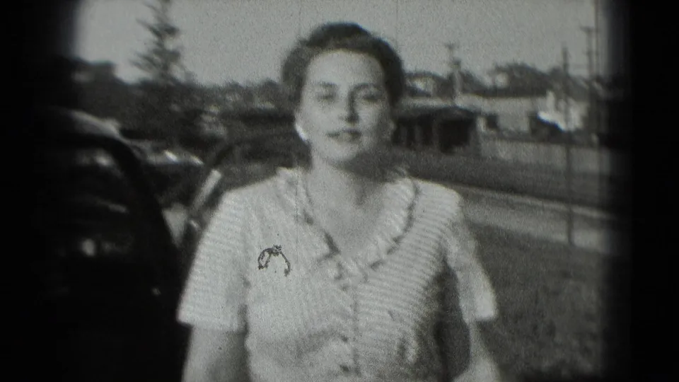 Smiling woman in a light dress faces the camera outdoors in Washington DC, with a vintage car and low buildings in the background.