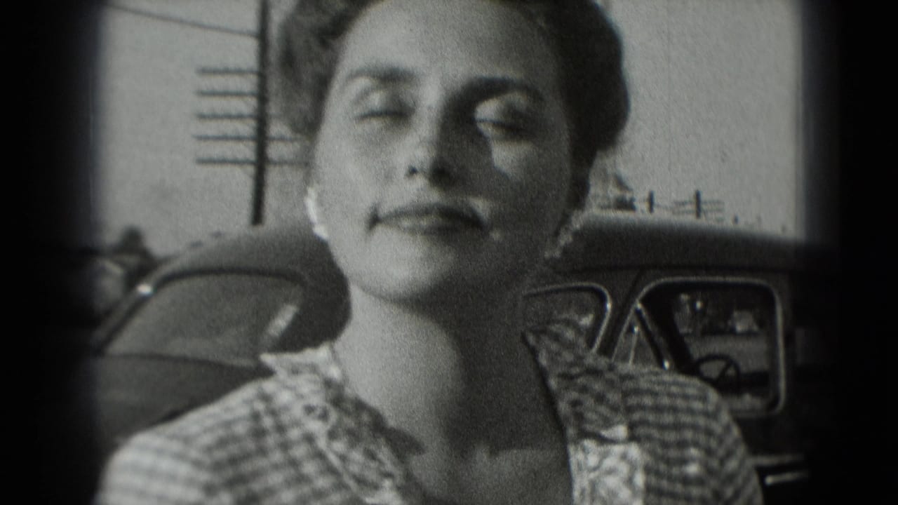 The woman pauses with her head slightly raised beside a parked car in the 1975 Washington, DC home-movie frame.
