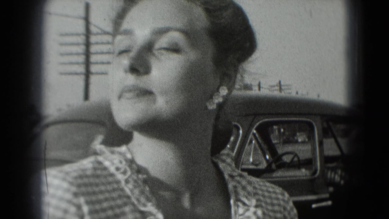 A woman in 1975 Washington DC home-movie footage stands near a car, her face turned slightly in bright light.