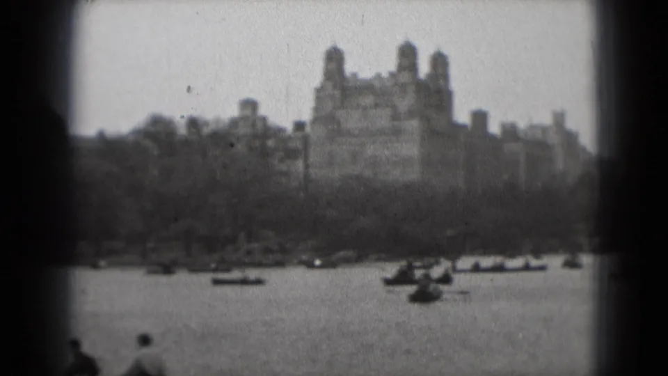 1975 Washington, DC home-movie view of rowboats on water with a large distant building beyond trees.