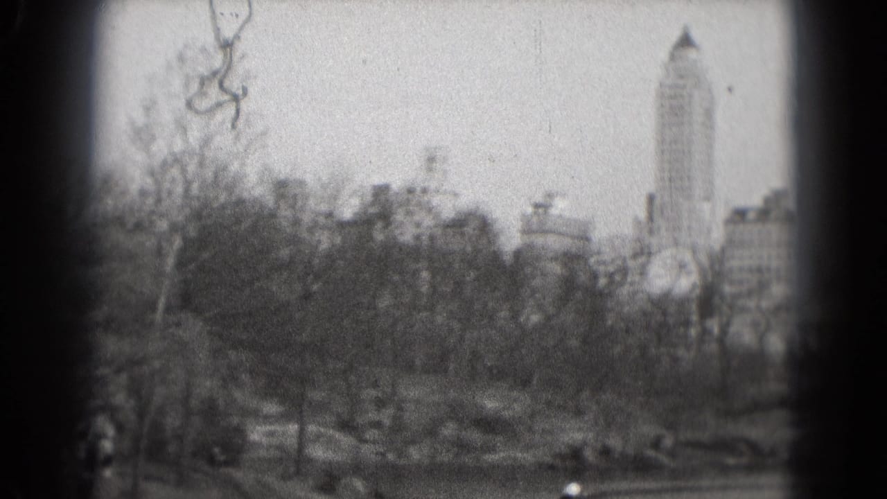 1975 8mm Washington, DC park scene with leafless trees, water, small boats, and a distant urban skyline.