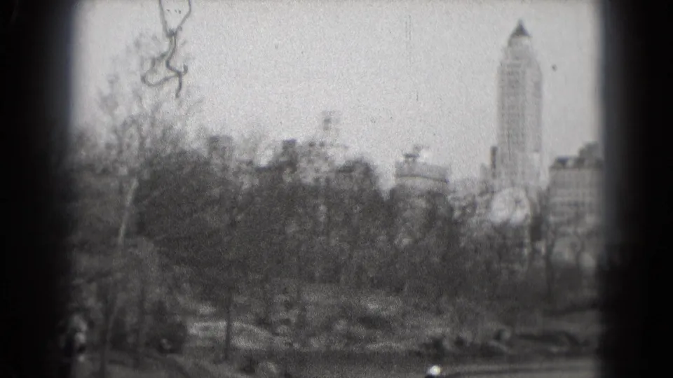 1975 8mm Washington, DC park scene with leafless trees, water, small boats, and a distant urban skyline.