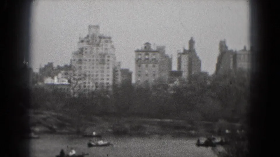 1975 Washington, DC home-movie frame showing a soft-focus skyline across a lake with small boats near the shore.