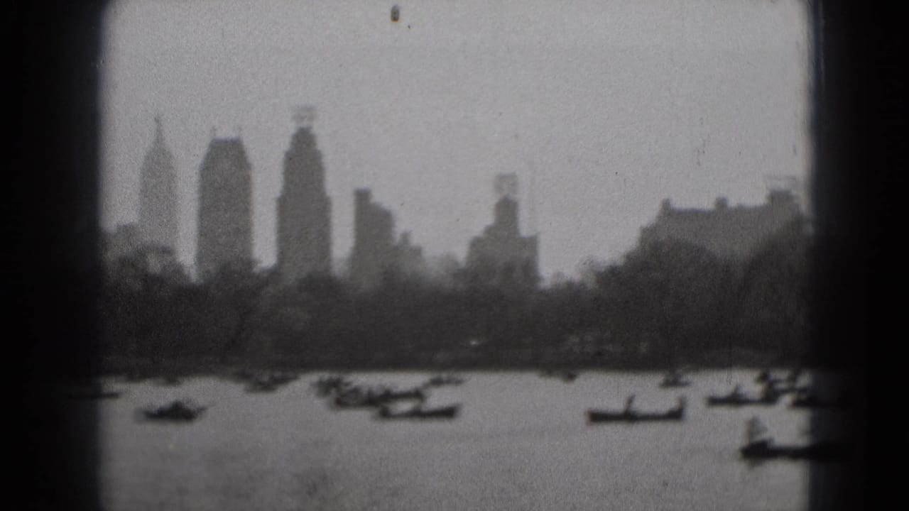 Boats cross a broad stretch of water below tall distant buildings.