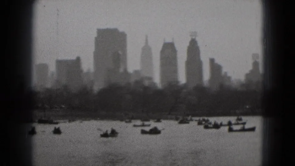 Hazy 1975 8mm view of small boats on water with distant city buildings and shoreline trees, location listed as Washington DC.