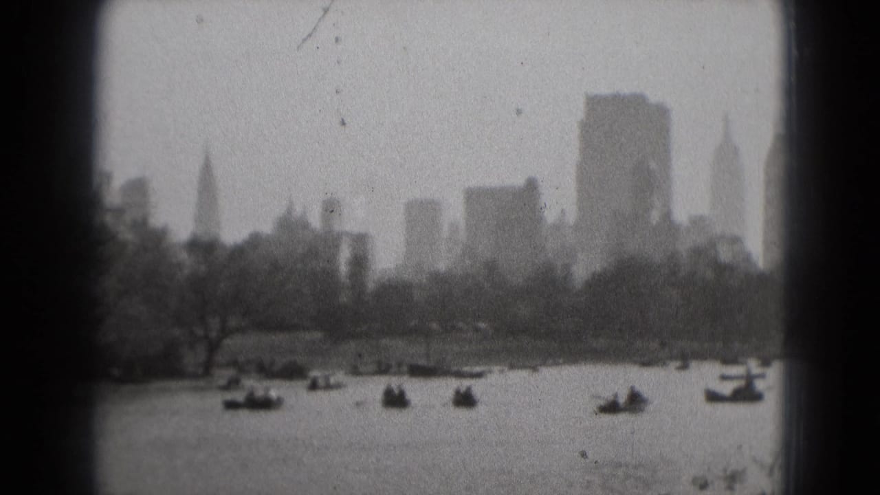 Washington DC waterfront scene from 1975 8mm film, showing scattered boats, trees, and distant buildings under cloudy haze.