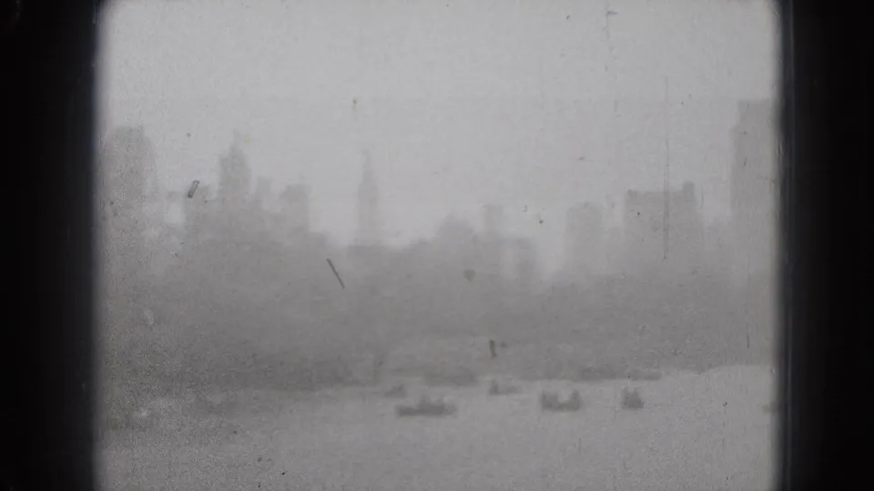Soft, washed 8mm frame of the Washington DC waterfront, with faint boats and skyline forms visible through haze.