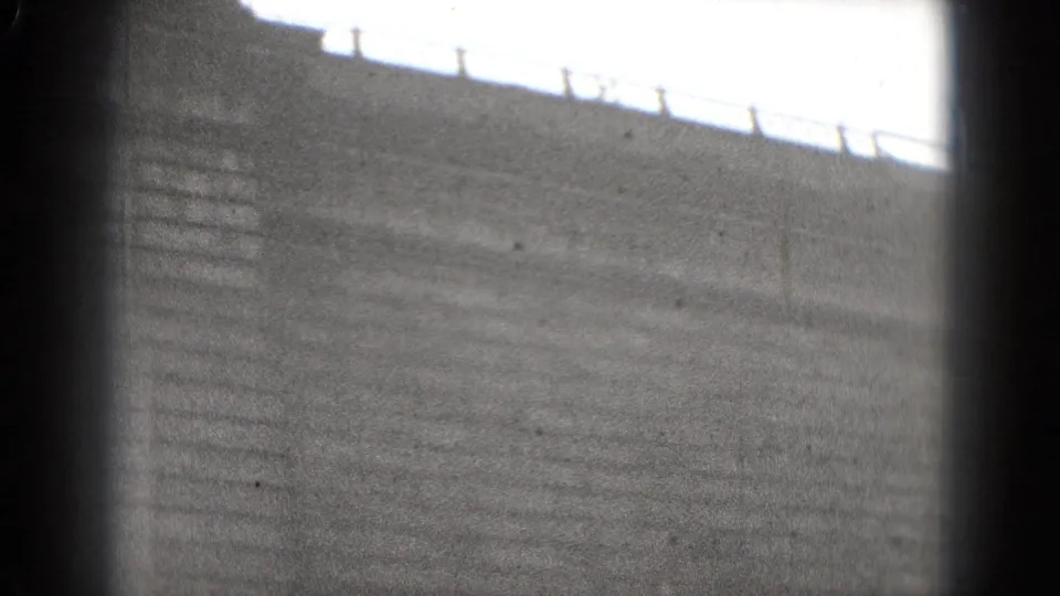 1975 8mm view shifts to a waterfront embankment or steps, with railing silhouettes along the upper edge.