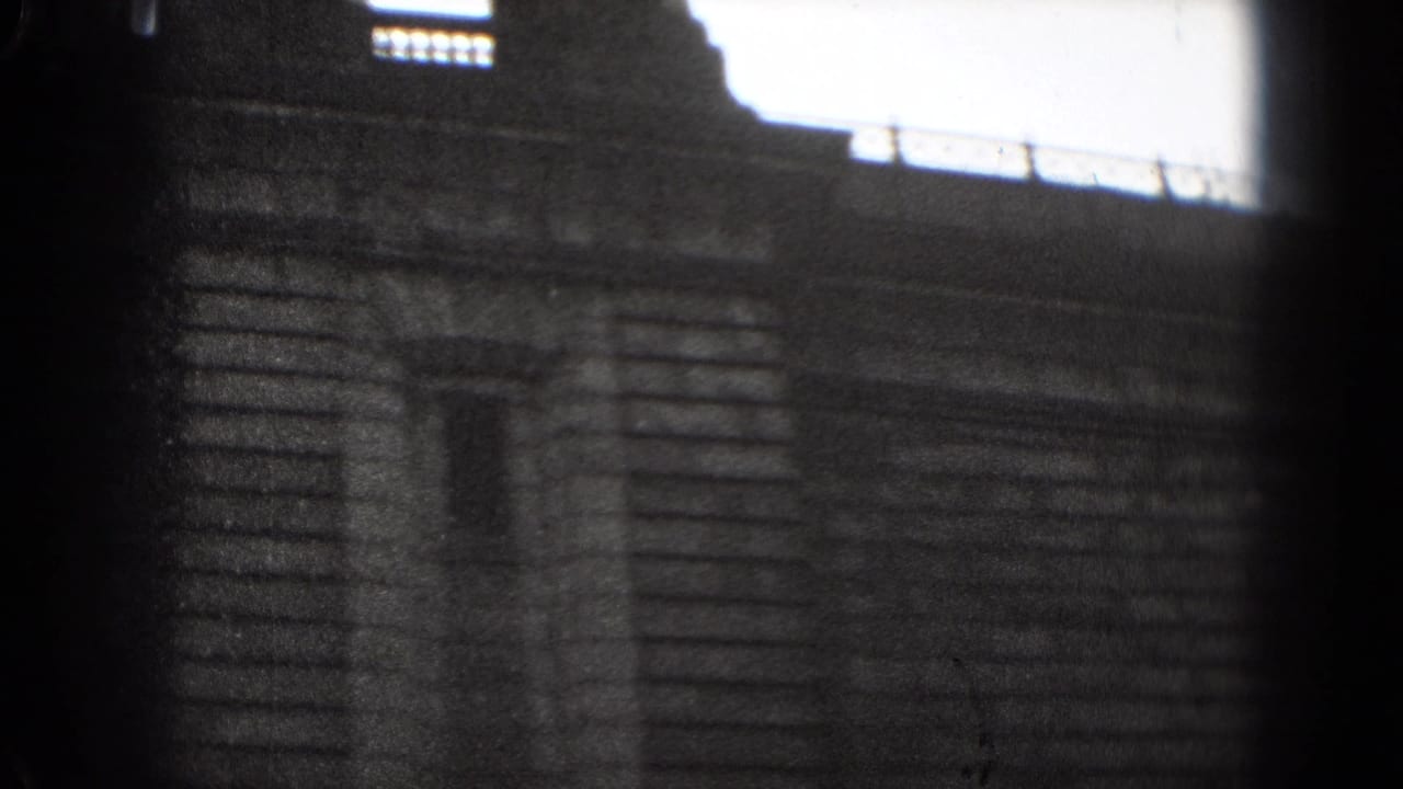 1975 Washington, DC 8mm frame showing a shadowed stone facade with bright rectangular windows and soft handheld framing.