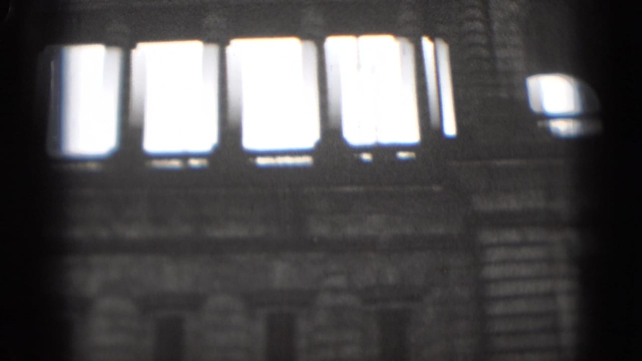 Close-up of tall bright windows set in a dark stone building wall.