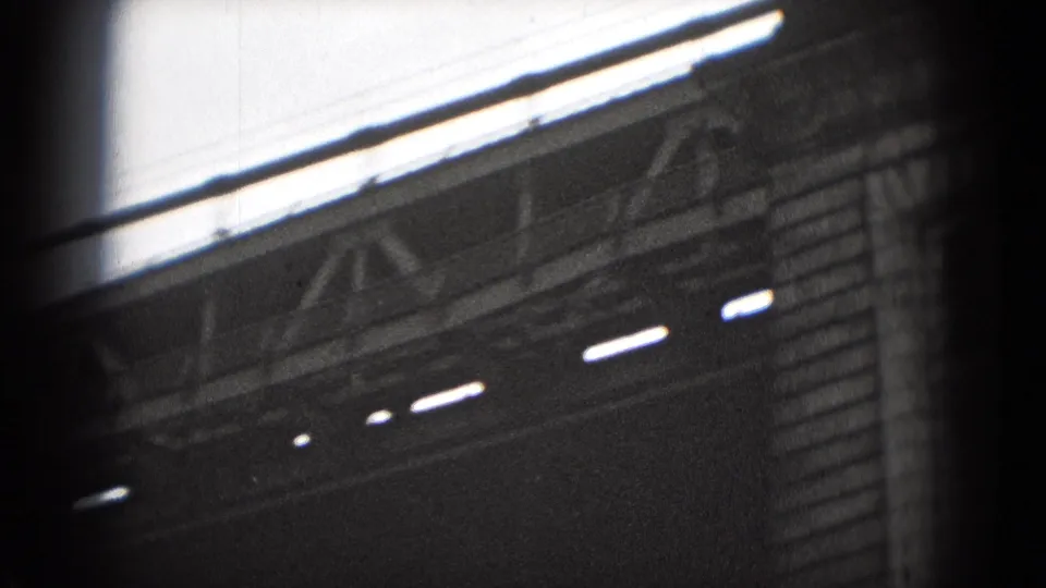 1975 Washington, DC frame showing an angled cornice, bright upper opening, and dark masonry facade in grainy 8mm film.