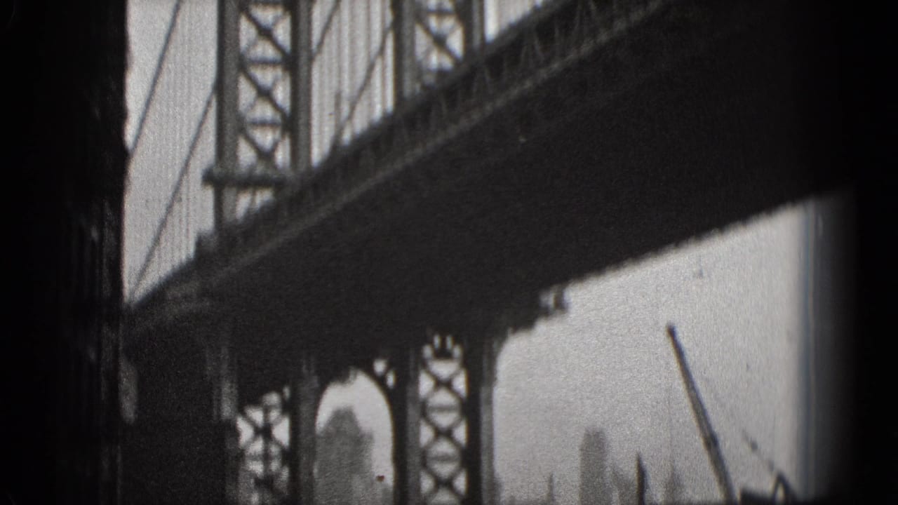 Black-and-white 1975 Washington DC 8mm frame looking beneath a steel bridge span toward water and hazy city structures.