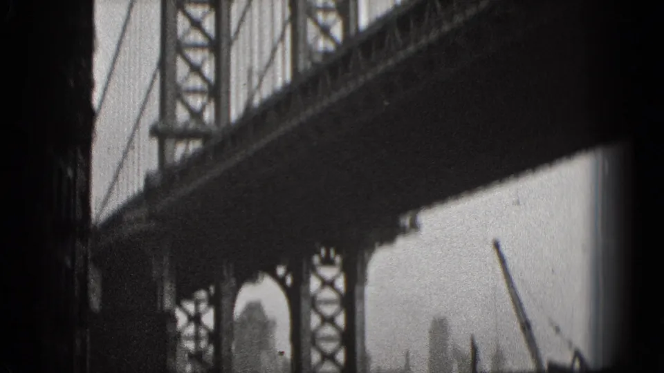 Black-and-white 1975 Washington DC 8mm frame looking beneath a steel bridge span toward water and hazy city structures.