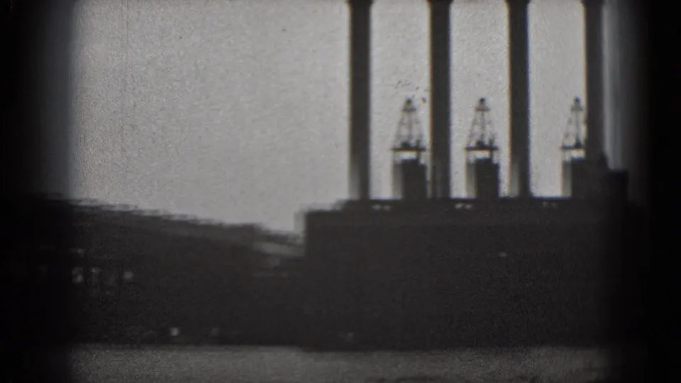 1975 Washington DC 8mm view of a distant industrial waterfront, with smokestacks and dark foreground bars crossing the frame.