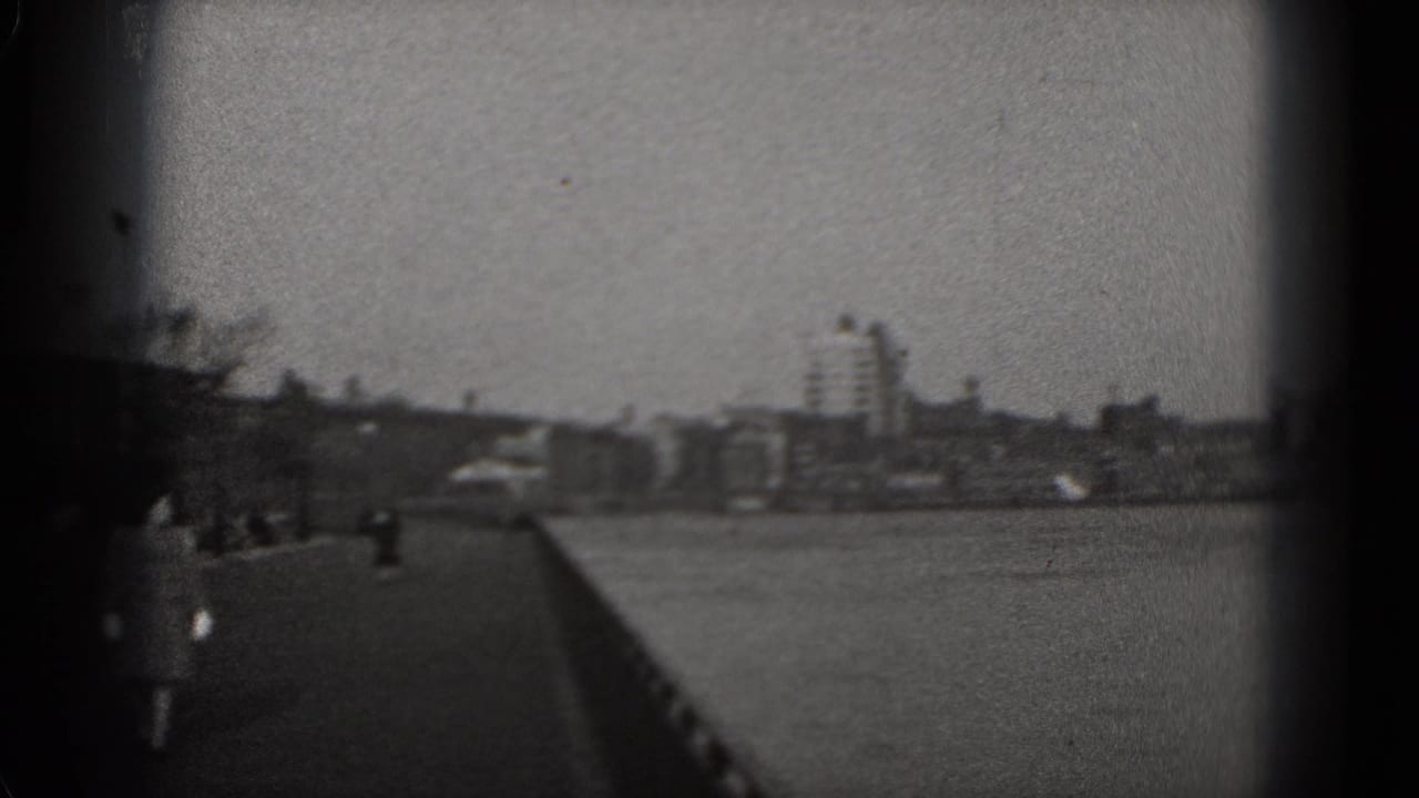 Washington, DC riverside promenade in 1975, showing pedestrians, railing and distant city structures.