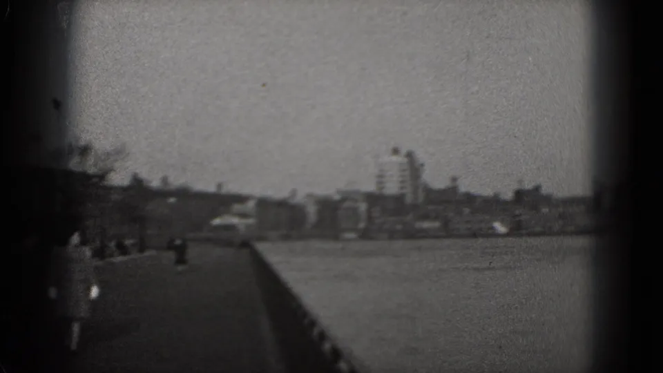 Washington, DC riverside promenade in 1975, showing pedestrians, railing and distant city structures.