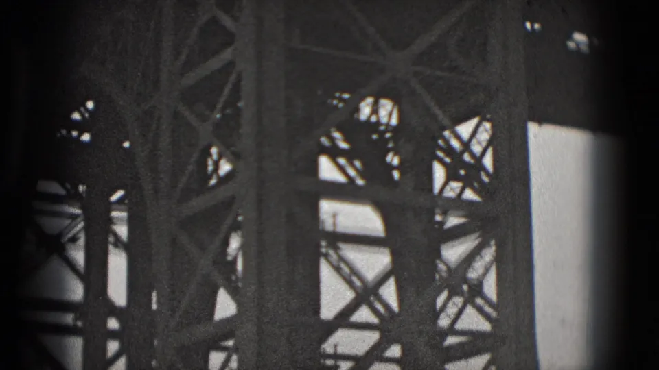 Black-and-white 8mm frame with close steel bridge trusses and vertical supports, likely from the Washington, DC bridge scene.