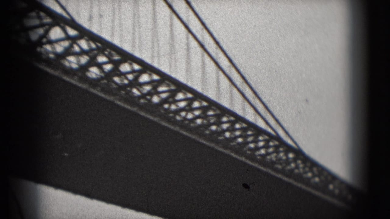 1975 8mm view from the Washington DC waterfront showing the underside of a bridge with lattice truss and suspension cables.