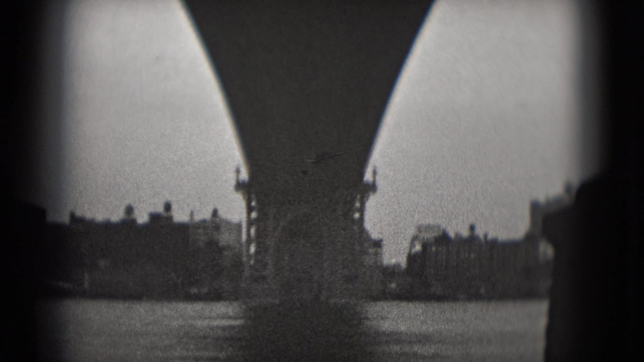 1975 Washington, DC 8mm frame showing bridge arches or supports with water and distant buildings beyond.