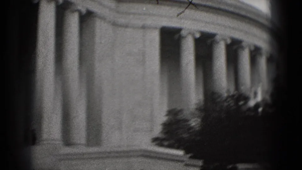 Black-and-white 8mm frame showing the Lincoln Memorial columns in Washington, DC, with trees and heavy edge vignetting.