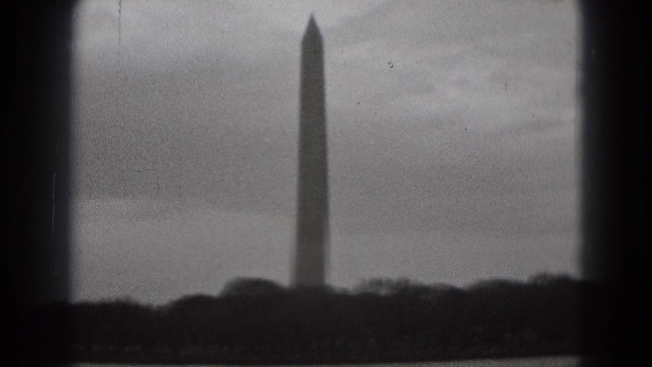 1975 8mm view of the Washington Monument rising beyond water and a dark shoreline in Washington, DC.