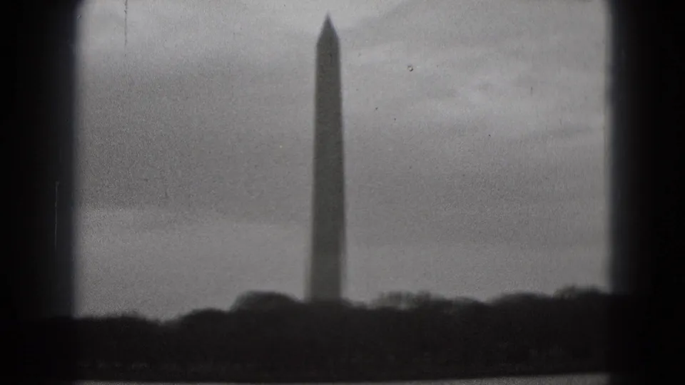 1975 8mm view of the Washington Monument rising beyond water and a dark shoreline in Washington, DC.
