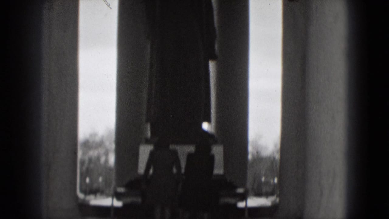 Black-and-white 1975 Washington, DC home-movie frame showing tall columns and silhouetted visitors inside a grand monument.