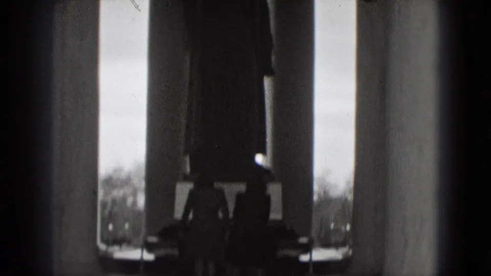 Black-and-white 1975 Washington, DC home-movie frame showing tall columns and silhouetted visitors inside a grand monument.