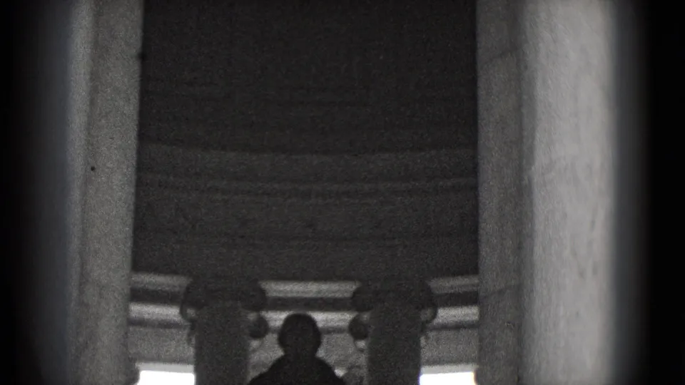 A 1975 Washington, DC home-movie frame shows a woman bowing or leaning near columns beneath a large statue.