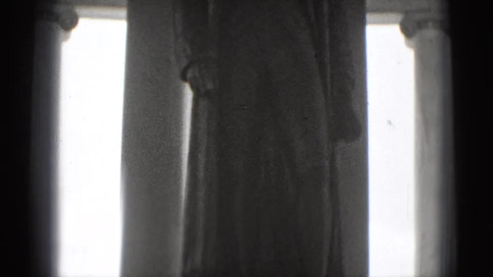 1975 Washington DC home-movie frame showing a close, soft view of a classical statue near tall monument columns.