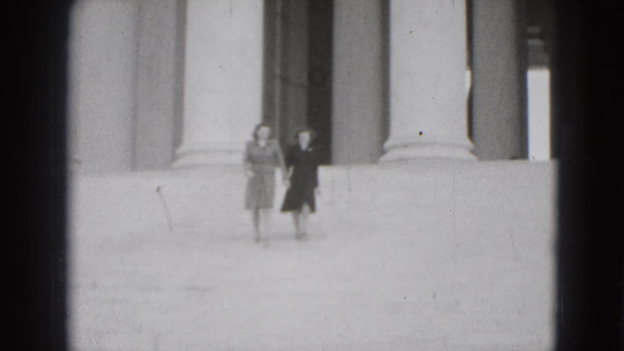 In 1975 Washington DC home-movie footage, two adult women appear small in frame near classical columns and wide stone steps.