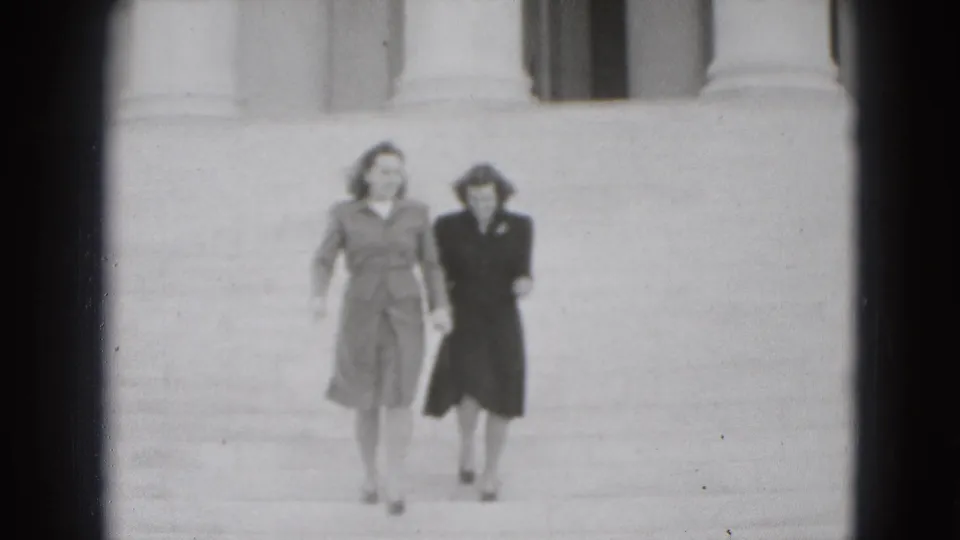 Near the end of the 1975 Washington DC clip, two adult women approach the camera on broad steps before a columned facade.