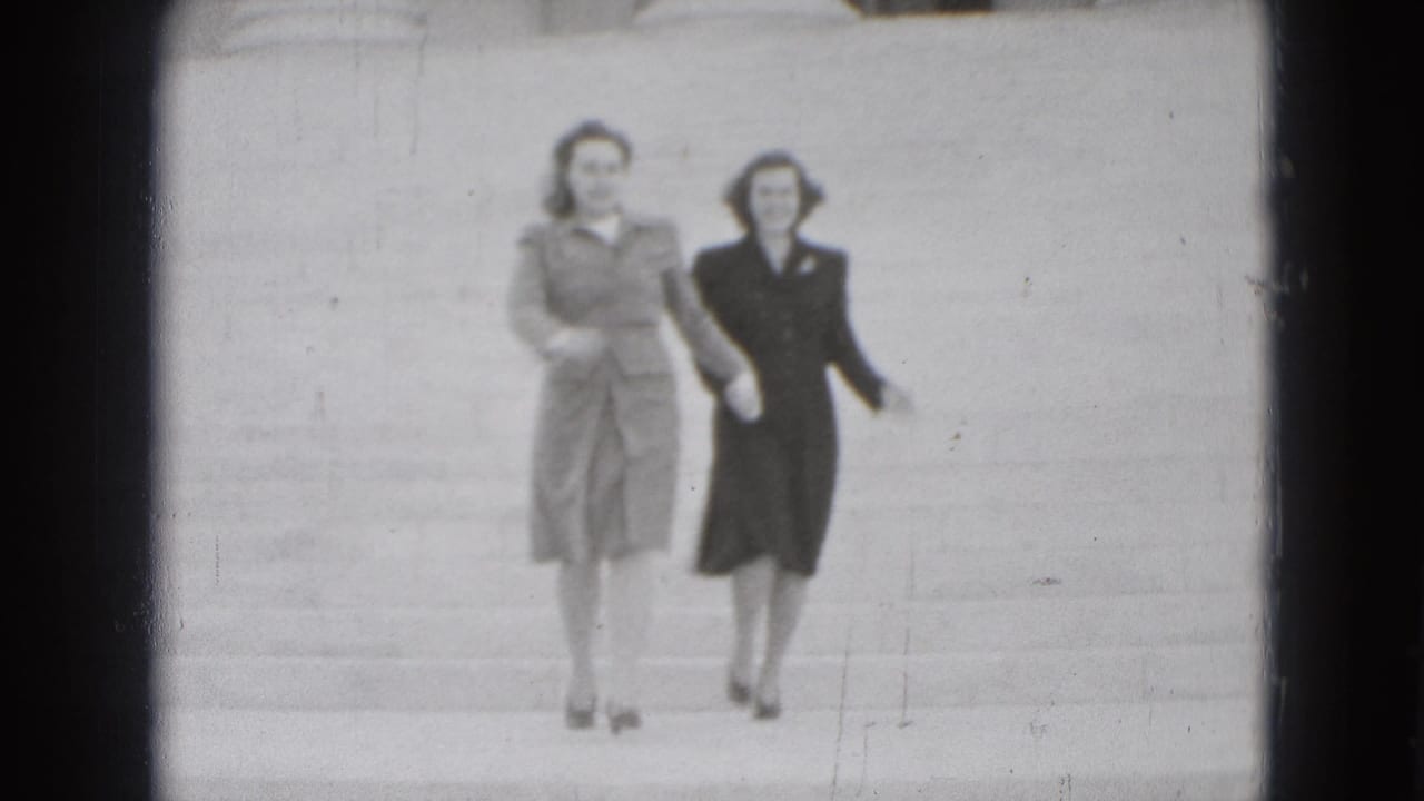 Two adult women in coats walk down broad stone steps outdoors.