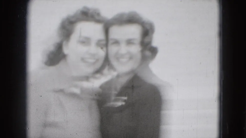 Two young women lean close together and smile in a blurred final frame of the 1975 Washington, DC home-movie scene.