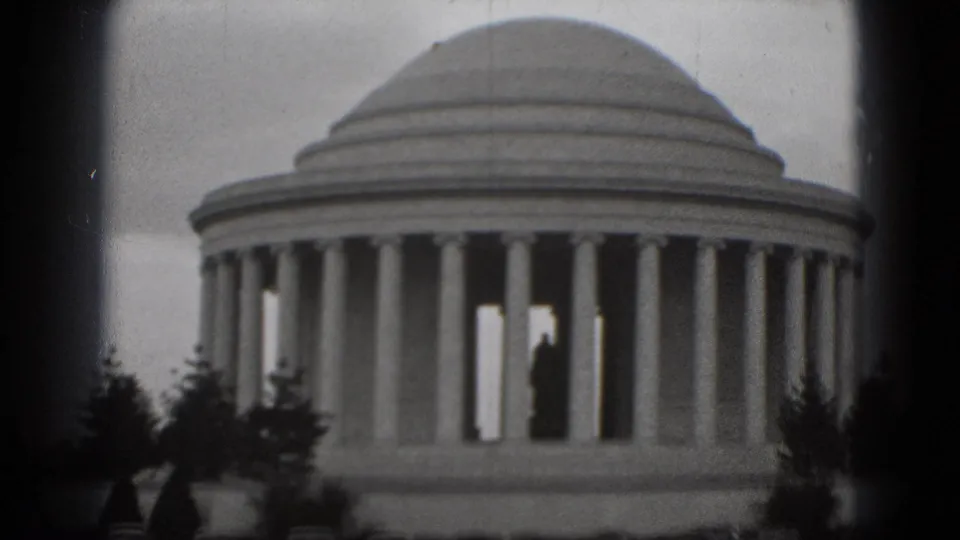 1975 Washington, DC 8mm frame showing the Jefferson Memorial columns and dome, with a distant visitor silhouette visible inside the structure.