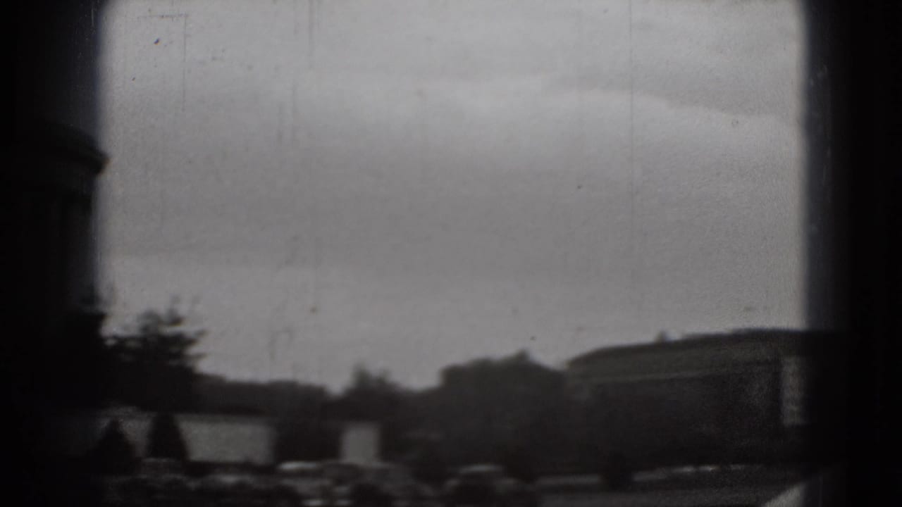 Distant Washington, DC view from the same 1975 8mm clip, with trees, low buildings, cars, and heavy viewfinder borders.