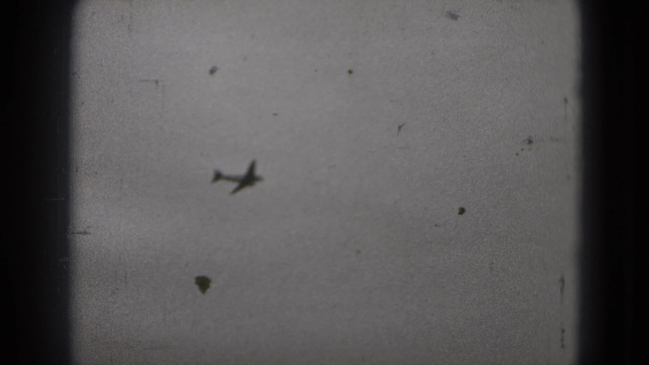 A distant airplane appears against a cloudy sky in grainy 8mm footage from the Washington, DC travel clip.