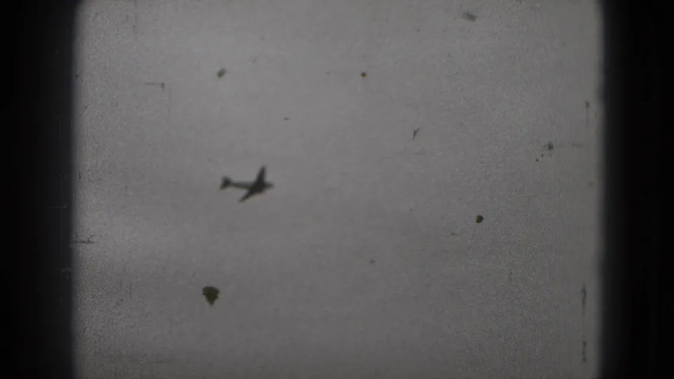 A distant airplane appears against a cloudy sky in grainy 8mm footage from the Washington, DC travel clip.