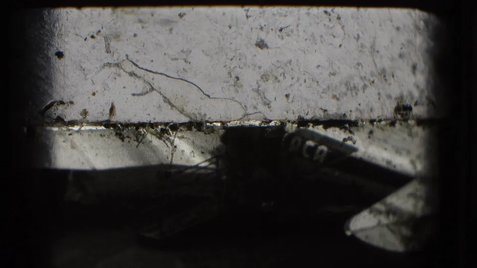 A close, partial view of a Capital Airlines aircraft appears in soft, scratched 8mm footage on the tarmac.