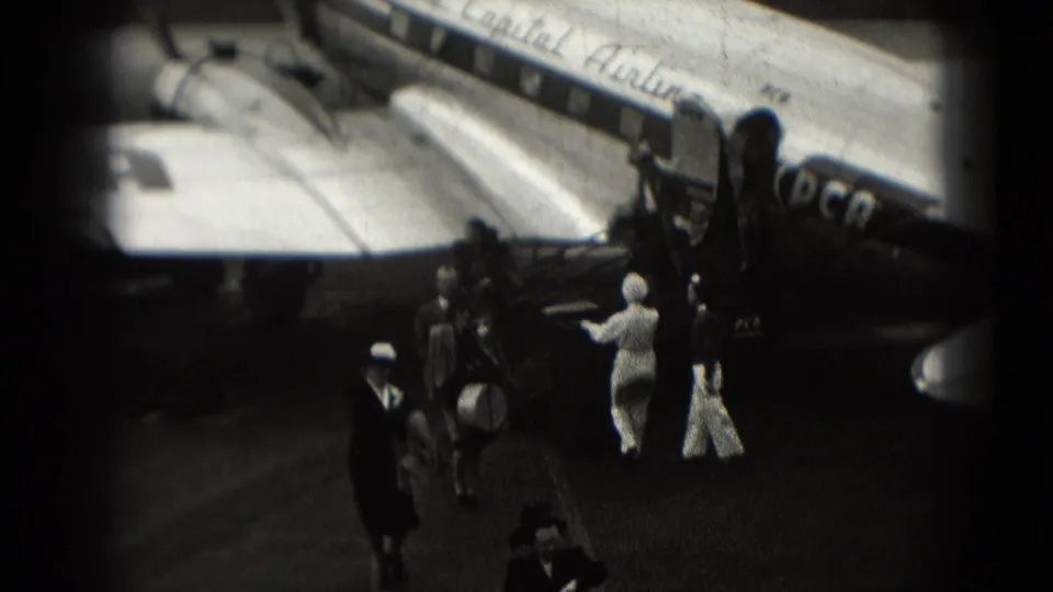 Passengers in period clothing gather near a Capital Airlines aircraft on a Washington, DC tarmac in 1975 home-movie footage.