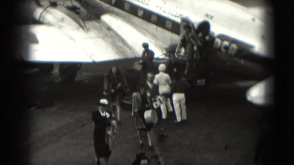 Passengers descend aircraft stairs and gather on the tarmac beside a Capital Airlines plane in 1975 Washington, DC footage.